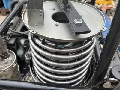 New heating coil being lifted into the boiler of a Nilfisk Contractor diesel hot pressure washer during repair.